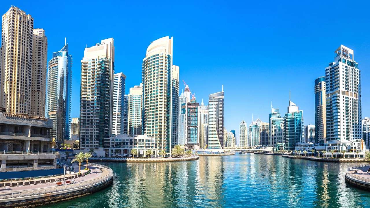 A panorama of modern skyscrapers surrounded by blue water under a clear blue sky