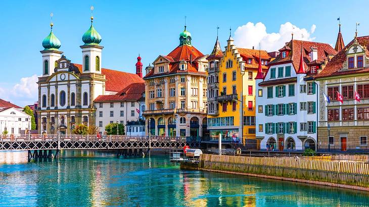 Multi-colored medieval buildings overlooking blue water with a bridge above