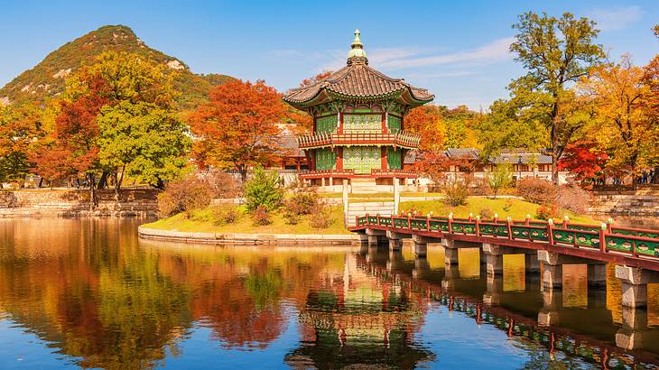 A palace with Korean architecture against autumn trees, overlooking water