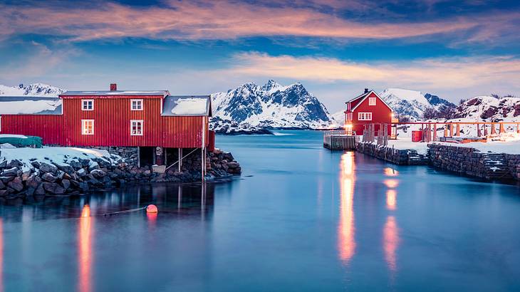 Red buildings next to icy blue water with a snowy mountain in the background