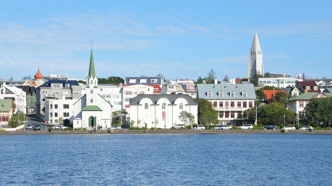 White buildings, a chapel, and a tower next to the water under a clear blue sky