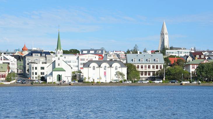 White buildings, a chapel, and a tower next to the water under a clear blue sky