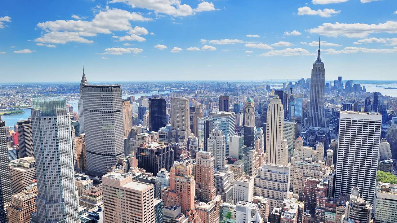 An aerial view of Manhattan with skyscrapers under a blue sky