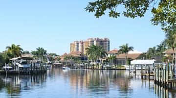 A waterway with boats on it next to palm trees and a multi-story building