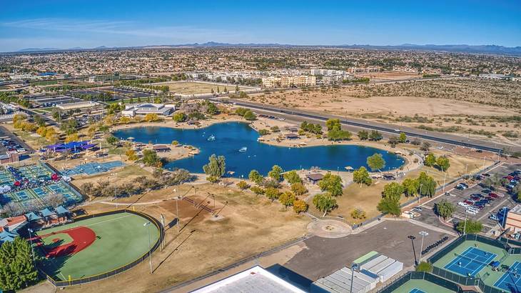 An aerial view over a city with buildings, a baseball field, and a lake