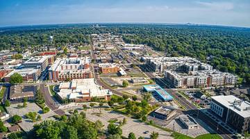 An aerial view of a city with buildings and trees under a blue sky