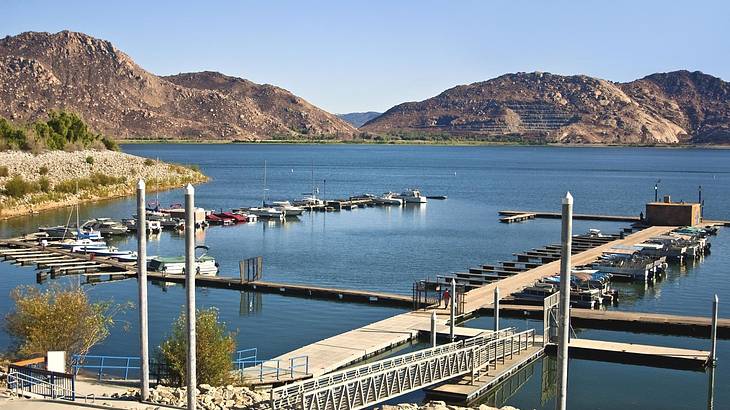 A lake with a boat dock surrounded by mountains under a blue sky