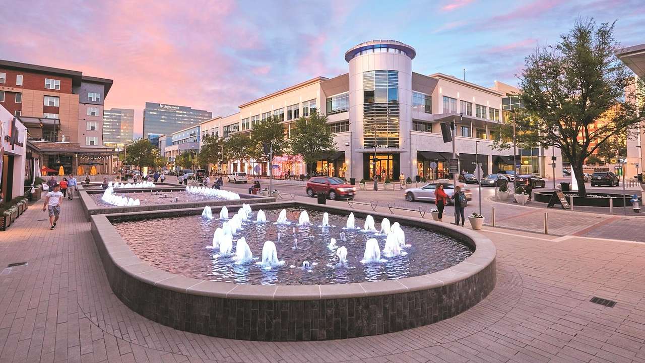 A fountain surrounded by a street and buildings under a purple sky