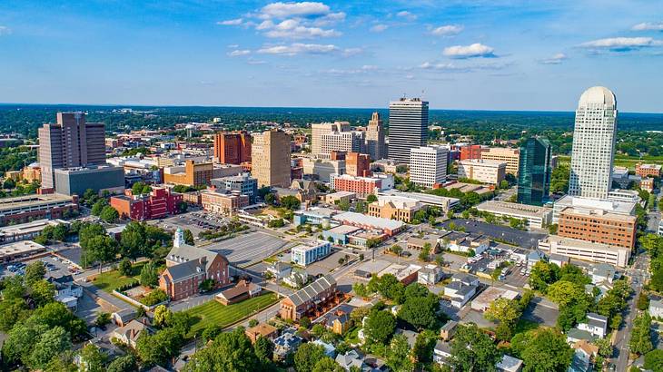 A view over a small city with buildings and trees under a blue sky