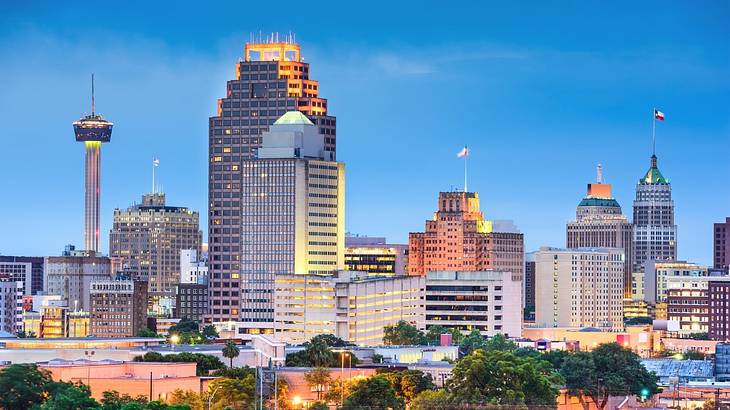 City buildings and an observation tower illuminated at night under a clear sky