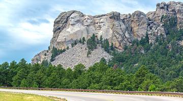 A road, grass, and lots of trees next to Mount Rushmore