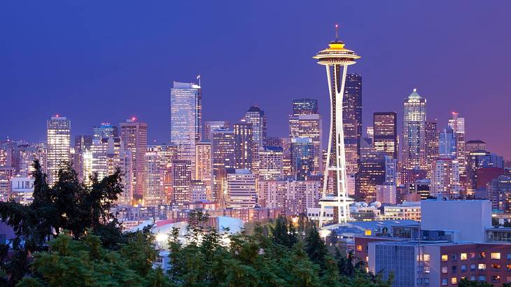 A city skyline at night with skyscrapers and an observation tower