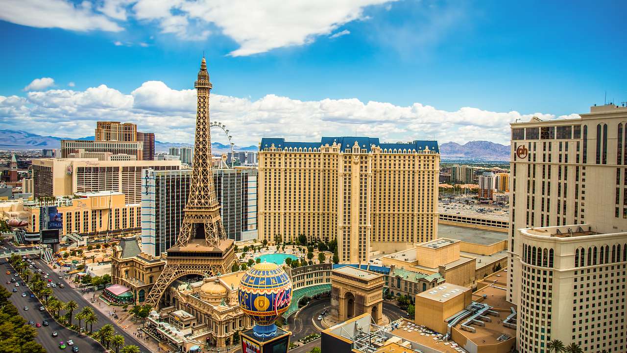 An aerial shot of a tall pointy tower surrounded by buildings and blue sky