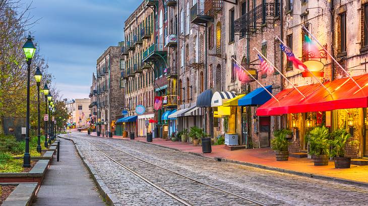 Lit up colorful historic buildings lining a cobblestone street with lampposts