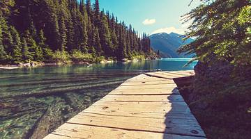 A boardwalk, blue water, trees and mountains at Garibaldi Lake, BC