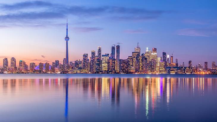 Top party cities in Canada - Toronto skyline behind water with a purple hue, Ontario