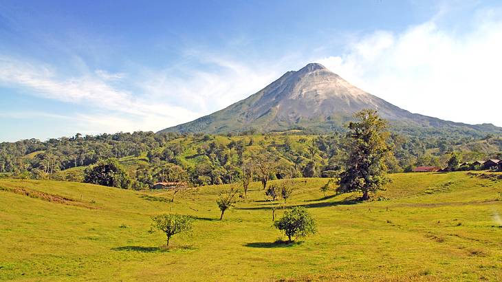A volcano peak in the background with green tree-filled hills in the foreground