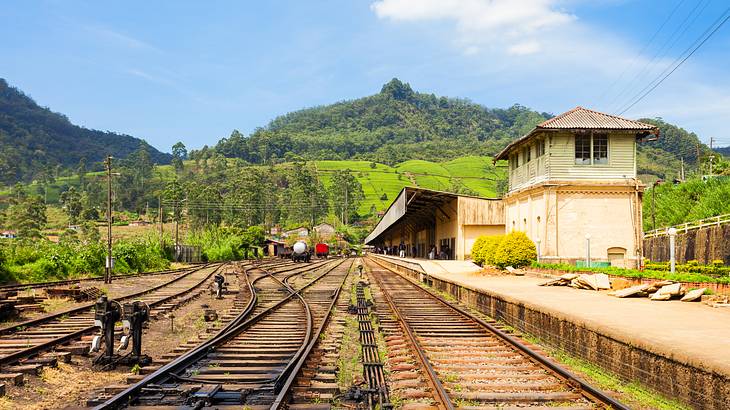 Several railroad tracks with a building on the right and mountains at the back Several railroad tracks with a building on the right and mountains at the back