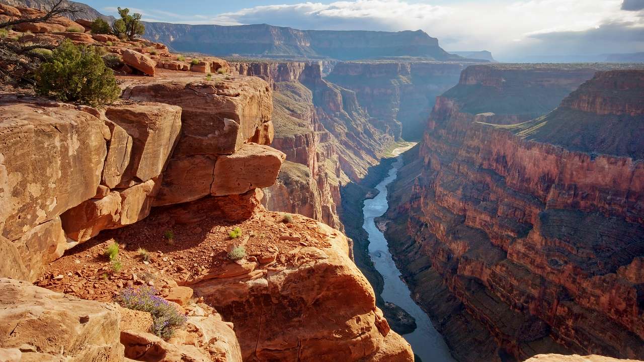 A river running through a canyon and a blue sky with mountains in the distance