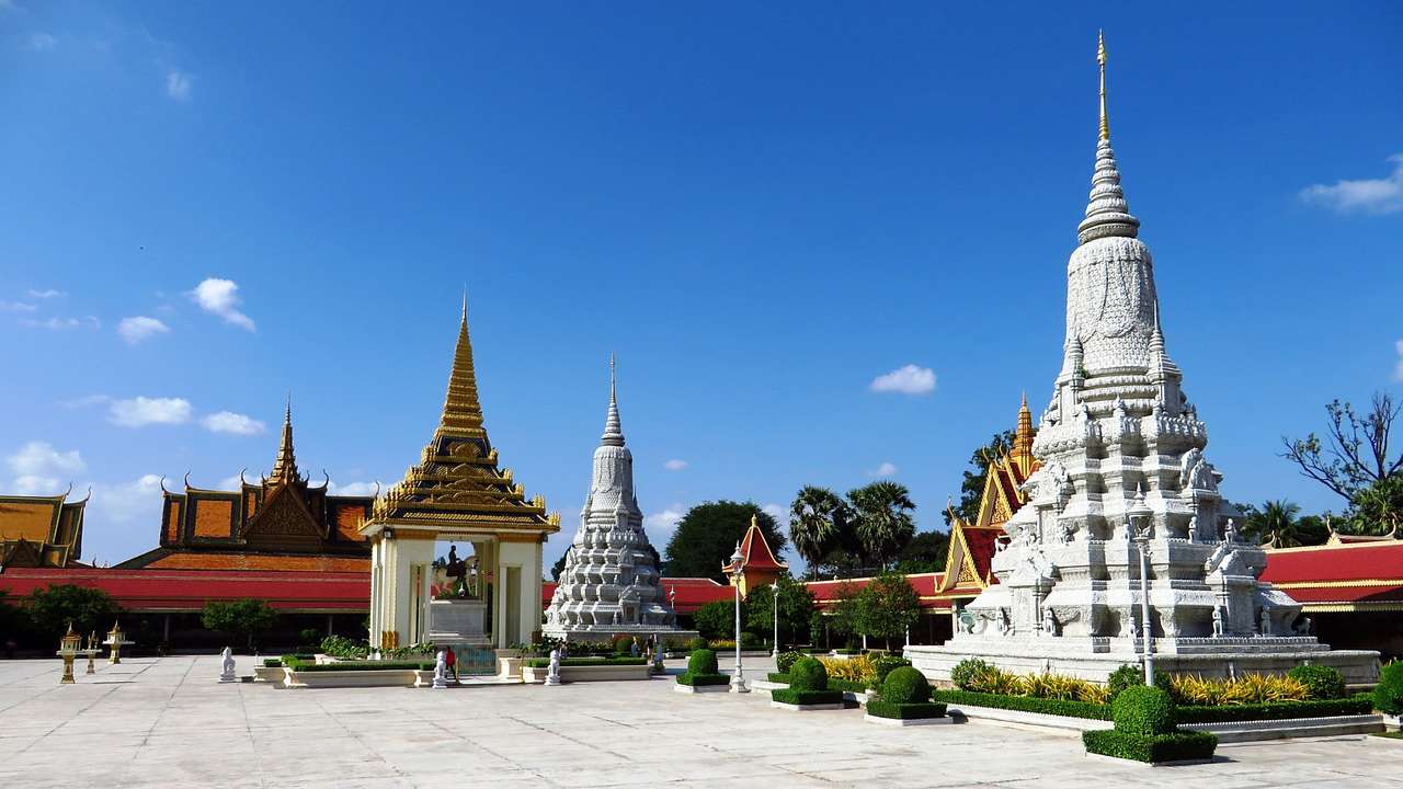A tower-like Asian sculpture next to smaller structures and a square with some bushes