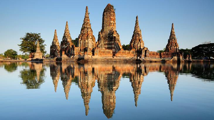 Ancient temples and shrines reflected in the water against a clear blue sky