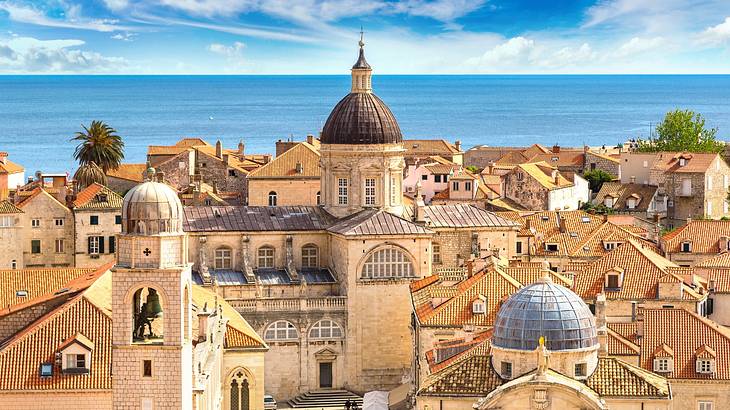 A view over a town with historic buildings, next to the sea under a blue sky