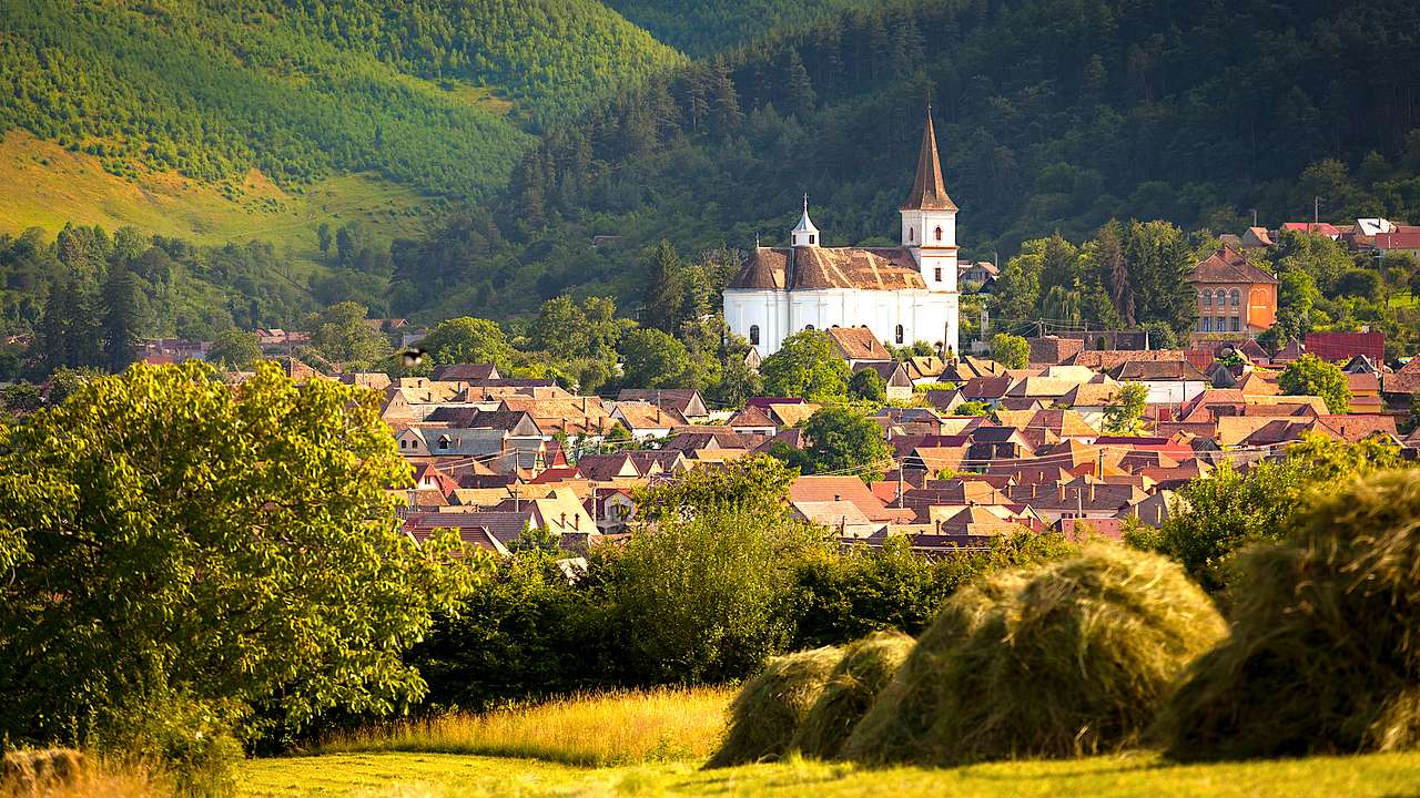 Transylvania itinerary - A church in between homes and green rolling hills, Sibiu
