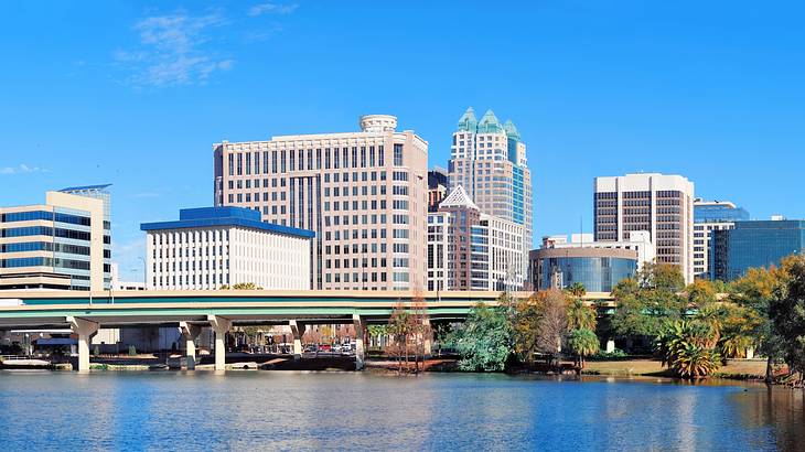A bridge over a body of water with buildings in the background and trees on the right A bridge over a body of water with buildings in the background and trees on the right