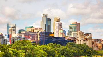 A downtown skyline with tall buildings and greenery in front