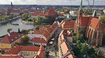 Ariel view of orange rooftops, churches and a river in Wrocław, Poland