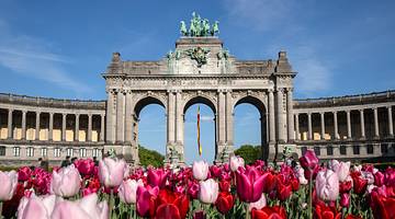 A large stone structure with three large arches and red tulip flowers in front