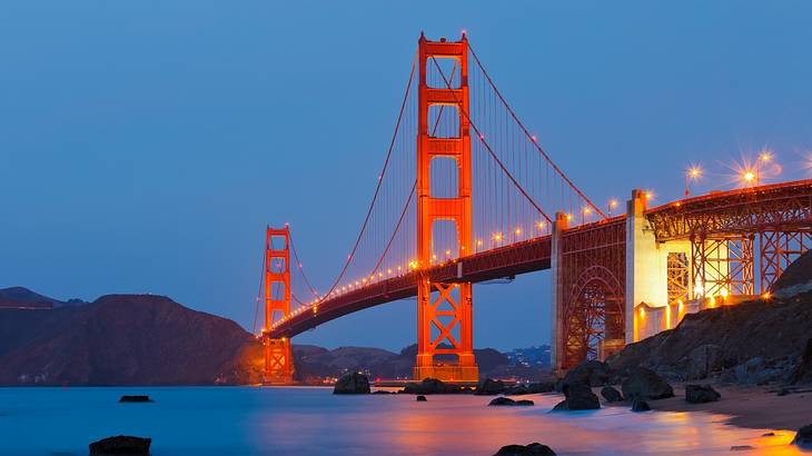 A red suspension bridge over a body of water at night