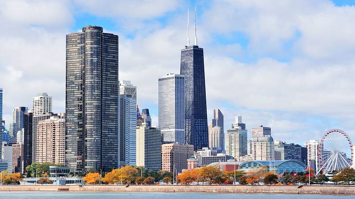 High rise buildings and a Ferris wheel under a blue sky with clouds