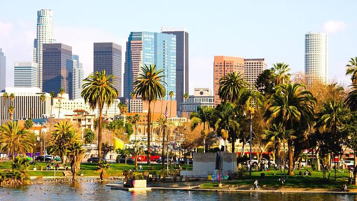 A city skyline with palm trees and water in front of it