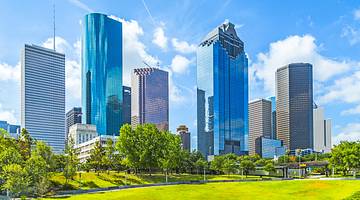 A walking path along a river with tall buildings behind a bridge A walking path along a river with tall buildings behind a bridge