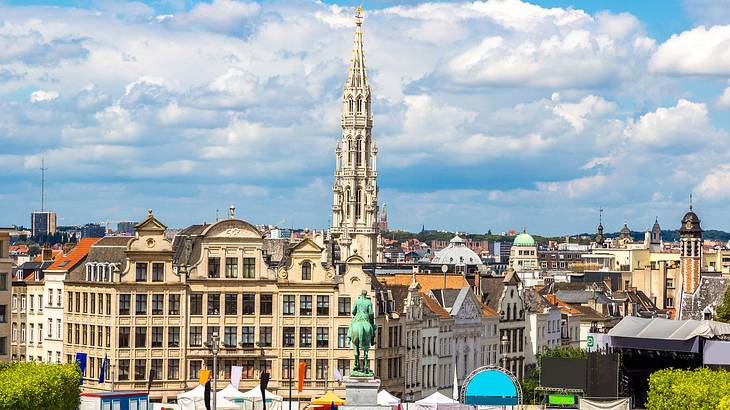 A European city skyline with historical buildings and a tall spire under a cloudy sky