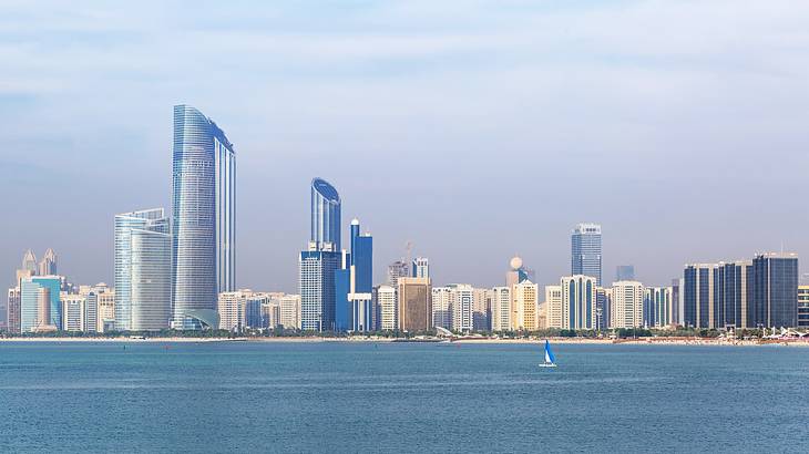 Cityscape with towering buildings and water in the foreground under the blue sky