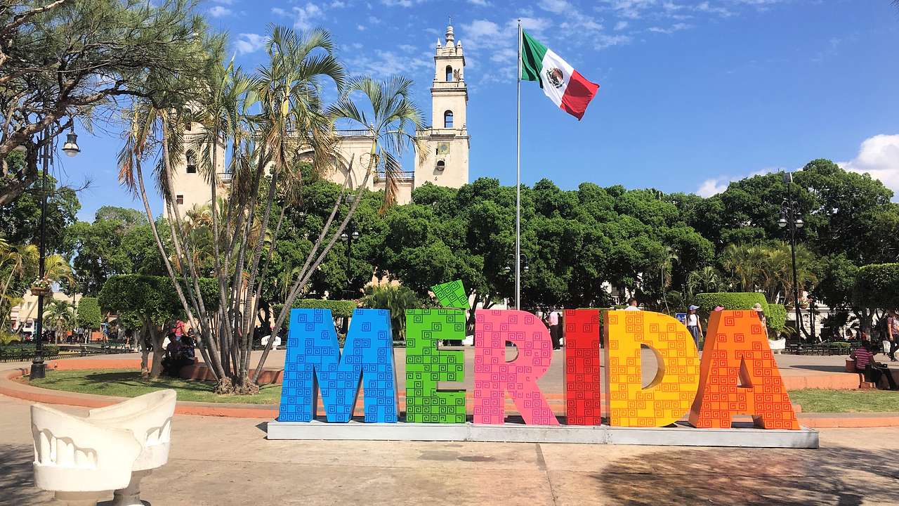A colourful sign that says "Mérida," with two intertwined chairs on the left