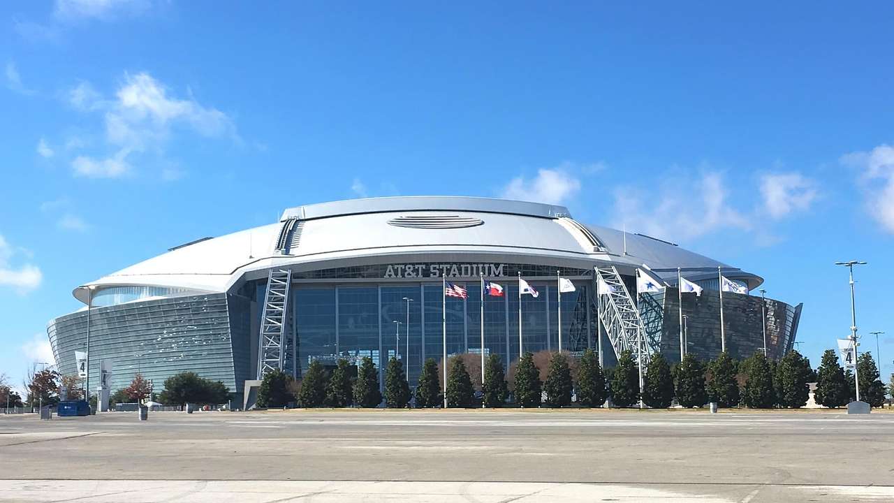 A football stadium with a sign that says "AT&T Stadium" and flags in front of it