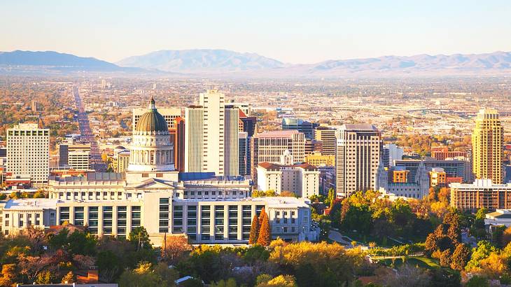 A view over a city with a large building with a dome next to trees and mountains