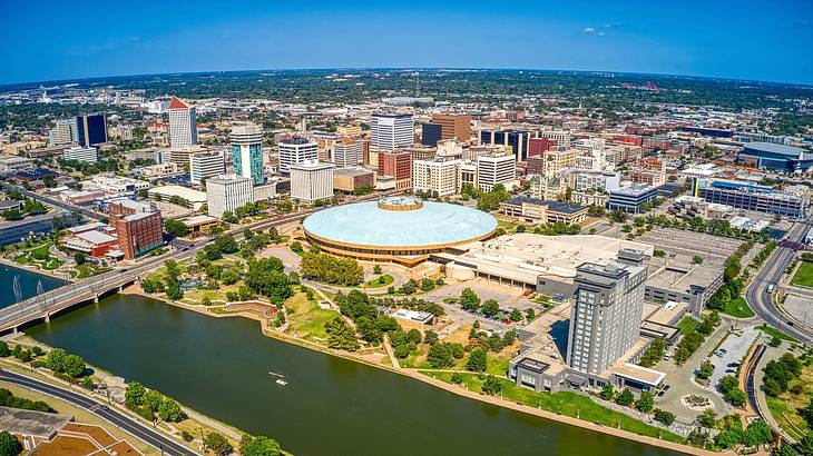 An aerial view of a city with a round building with a blue roof next to a river