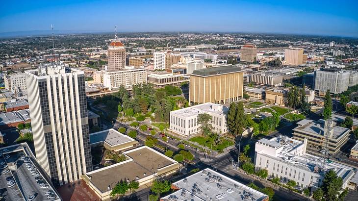 A view over a city with buildings and trees under a blue sky