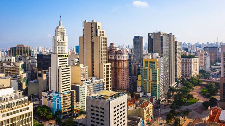 A city skyline with tall and short buildings under a blue sky