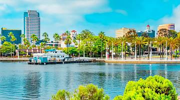 Blue ocean water with greenery in the foreground and buildings on the shore