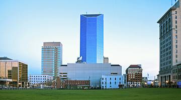 City buildings next to the grass under a blue sky