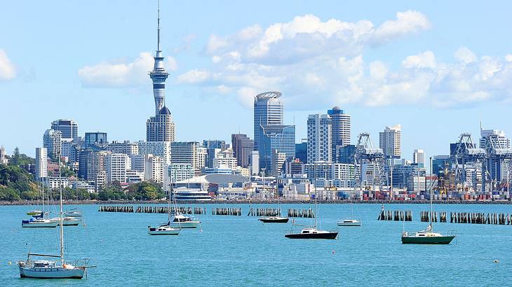 A city skyline with many buildings next to the water with boats on it