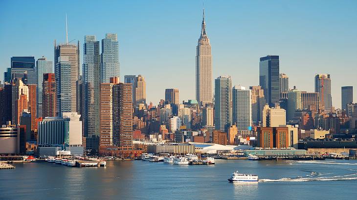 The Manhattan skyline with skyscrapers and water with boats on it in front