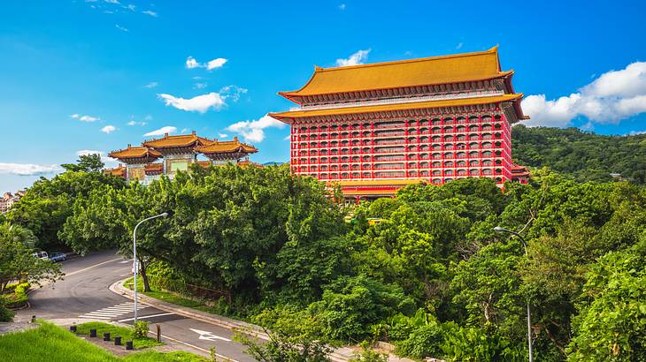 A yellow and red temple-like building next to green trees