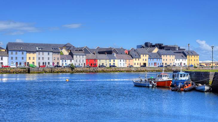 A body of water near colorful buildings and boats docked by a port