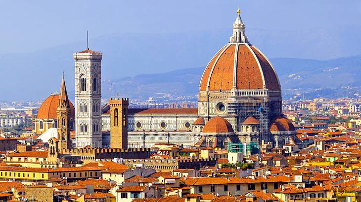 A tall church amidst several houses and buildings with a distant view of mountains